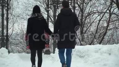 年轻夫妇在冬天的公园里散步，手里拿着雪。 冬闲的幸福恩爱夫妻.. 回去
